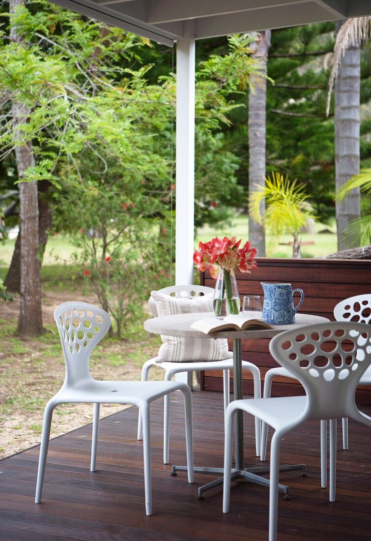 weiße Designer Outdoormöbel auf Holzterrasse eines Wochenendhauses im Wald