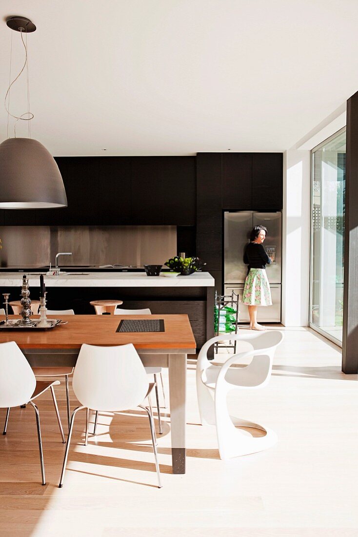 Modern, open-plan kitchen with brown cupboards, floor-to-ceiling glass wall & dining area