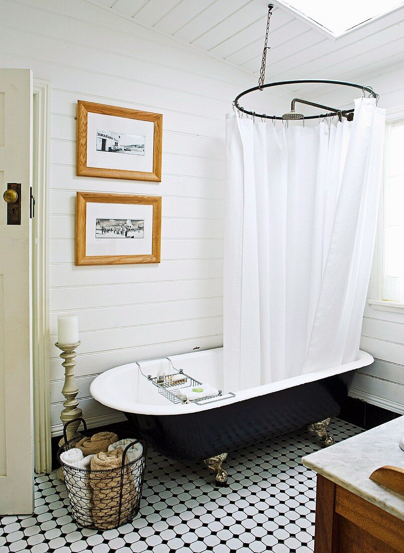 Vintage bathtub with shower curtain in country-style, wood-clad bathroom with tiled floor
