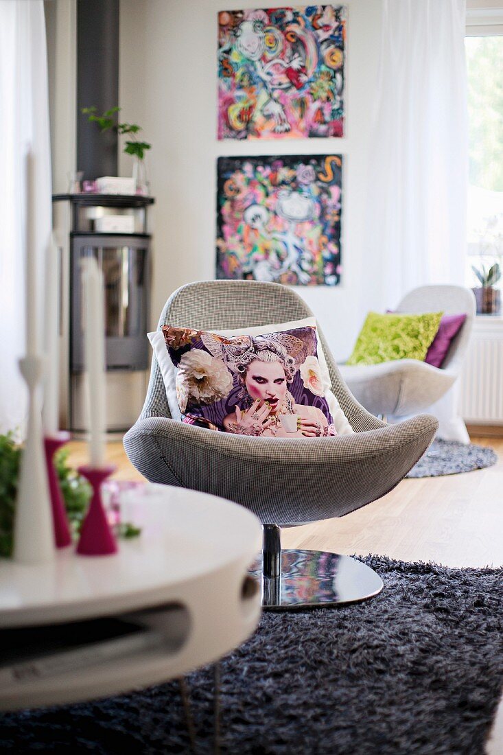Scatter cushions on swivel easy chair on grey, long-pile rug in modern interior