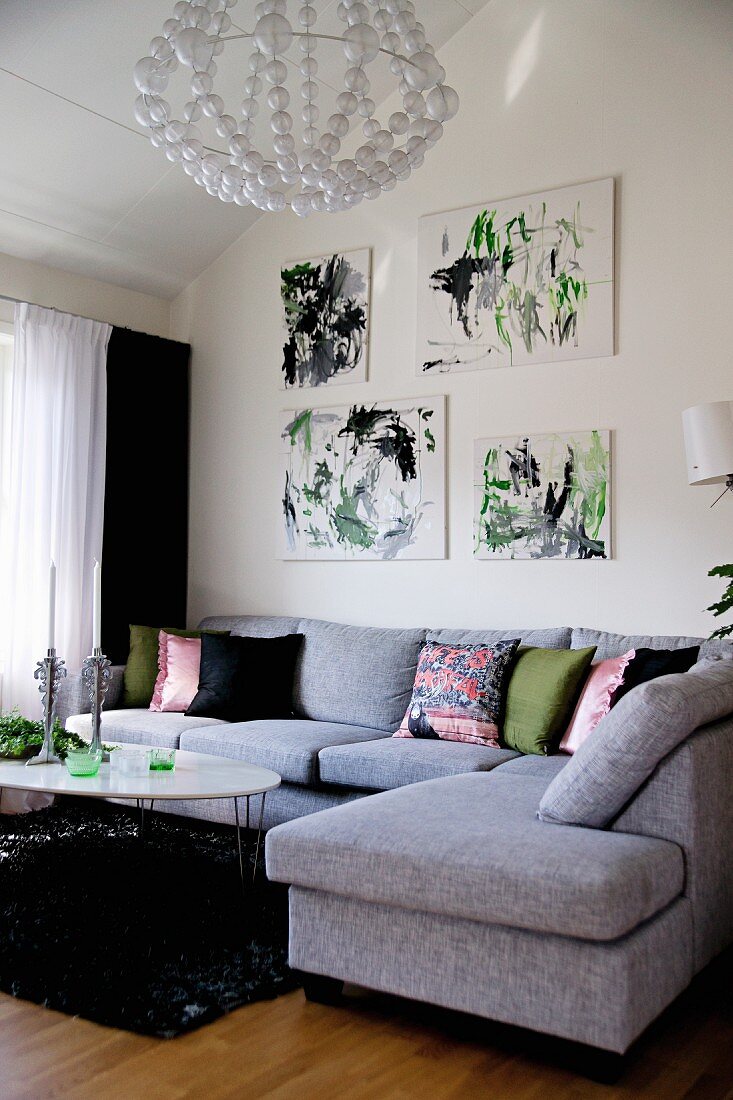 Modernes, hellgraues Sofa übereck im Wohnzimmer, an Wand Zeichnungen