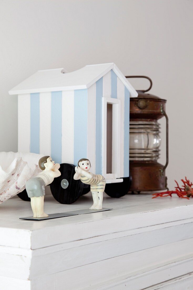 Maritime ornaments - miniature, blue and white stripes beach hut and small figurines on white cabinet