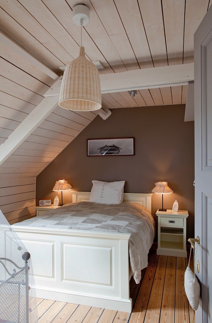 Holzverkleidetes Schlafzimmer mit weißem Doppelbett unter dem Dach