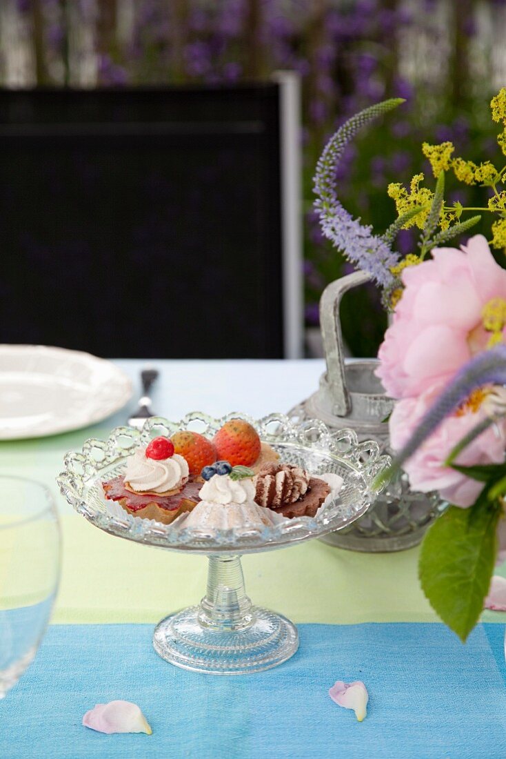 Gedeckter Tisch mit Dessert und Blume im Garten