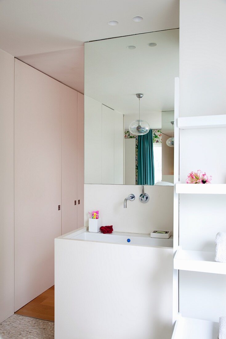 Contemporary bathroom with white panelled washstand in niche and fitted cupboards in background