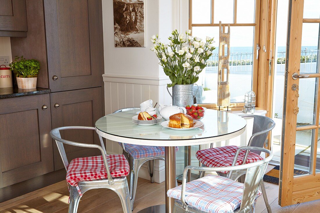 Esszimmerecke - Klassikerstühle aus Metall um runden Tisch vor offener Terrassentür