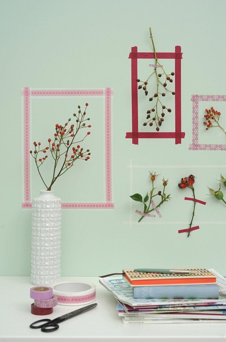Picture frames of washi tape around sprigs of rose hips on wall