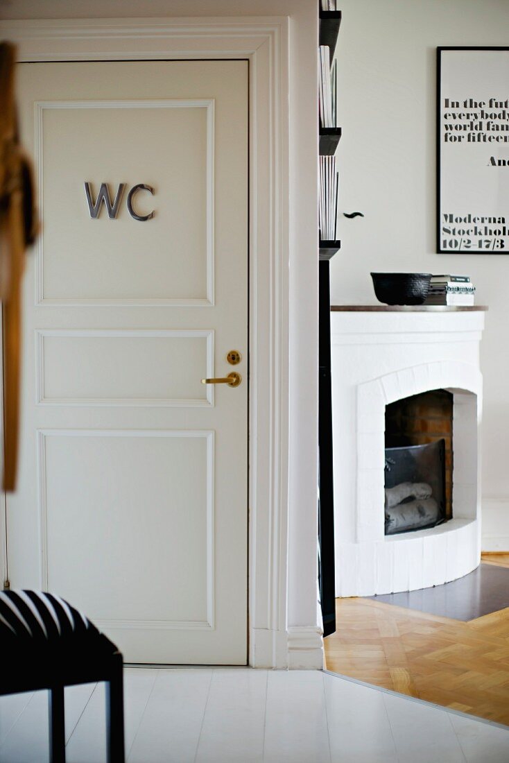 Open corner fireplace next to white interior door with WC sign