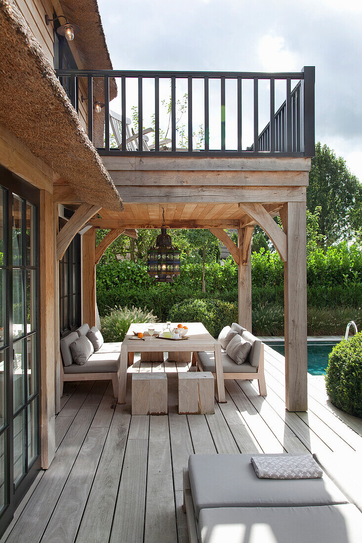 Überdachte Terrasse mit Essbereich und Lounge-Möbeln am Pool