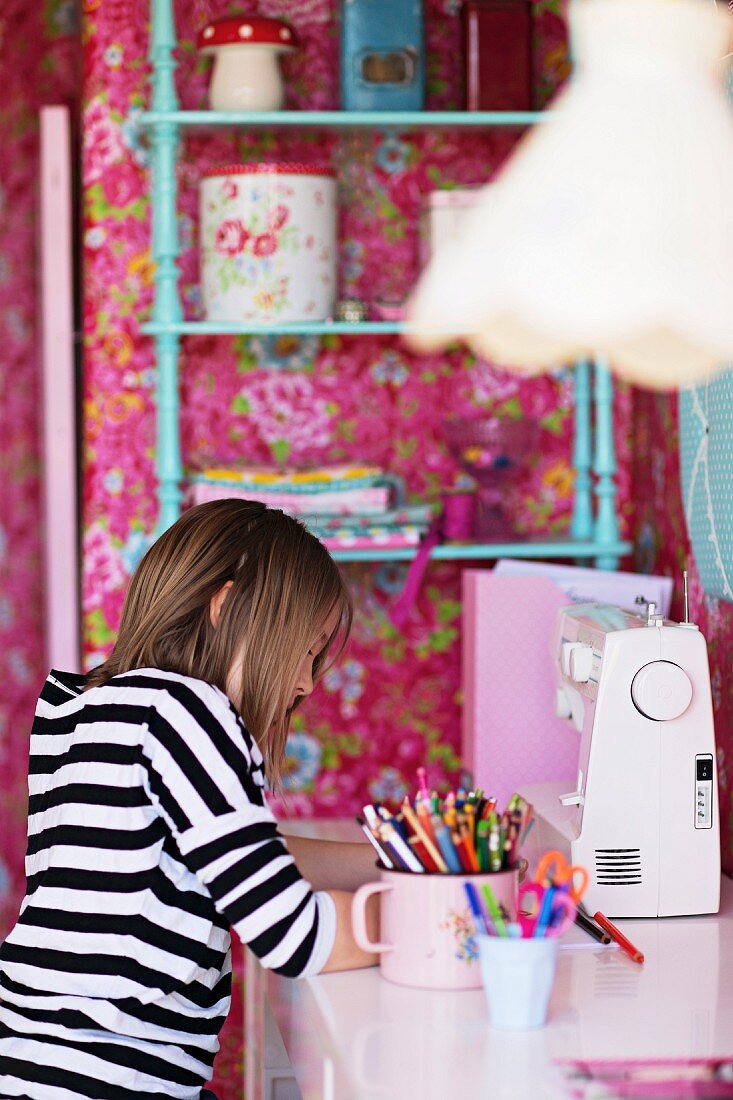 Junges Mädchen am Schreibtisch in nostalgisch gestaltetem Kinderzimmer