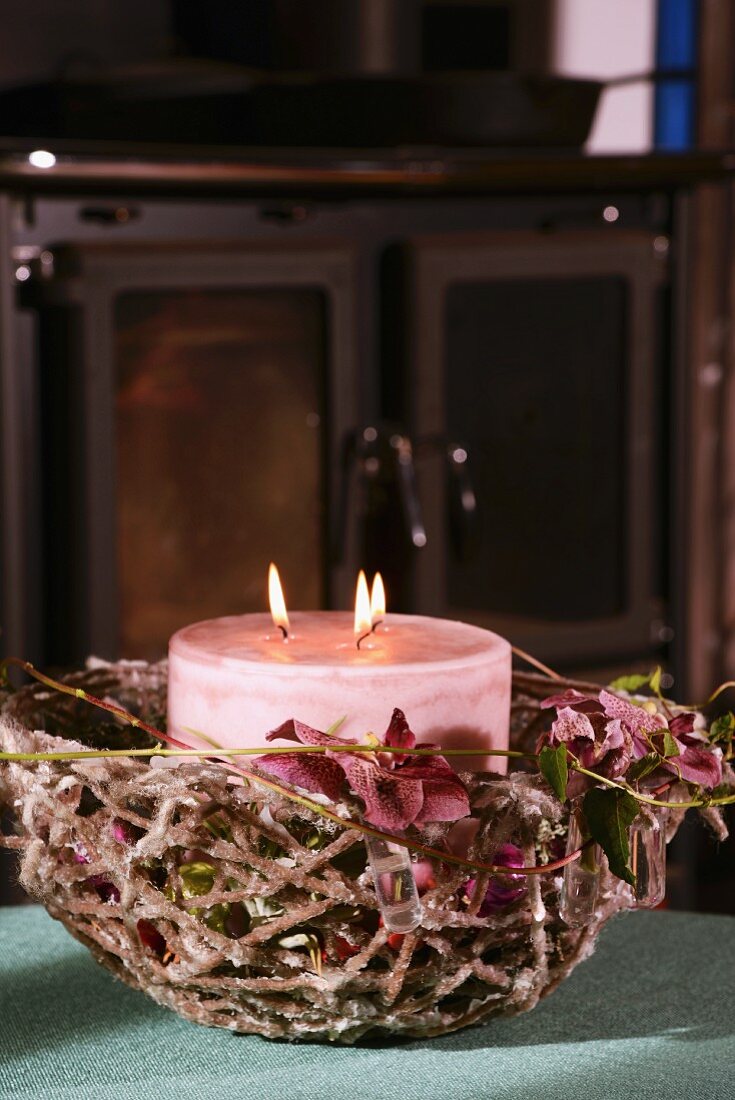 Aus dicker Wolle gefertigter Korb mit dicker rosafarbener Kerze