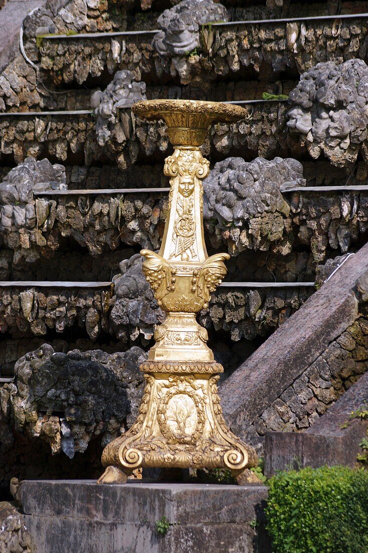 An oversized gilded candlestick on a stone plinth in the Garden of the Palace of Versailles