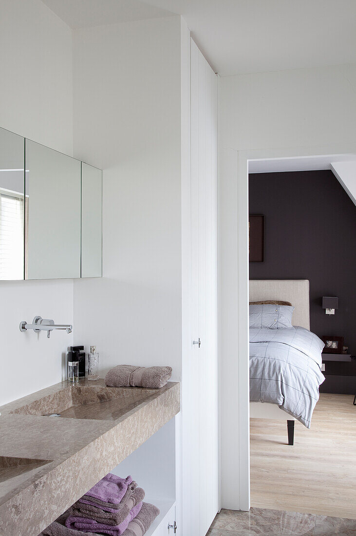 Bathroom with washbasin and mirror, view into adjoining bedroom