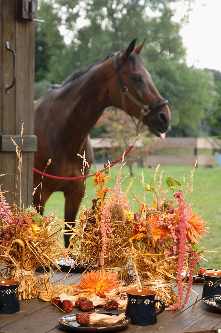 Bundles of straw decorated with flowers; horse in background