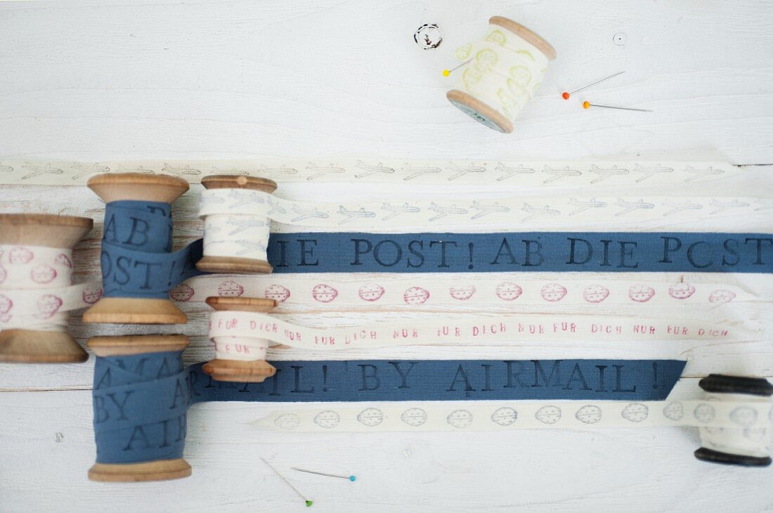 Selbst bedruckte Stoffbänder in weiss und blau auf Vintage Holz-Garnrollen gewickelt