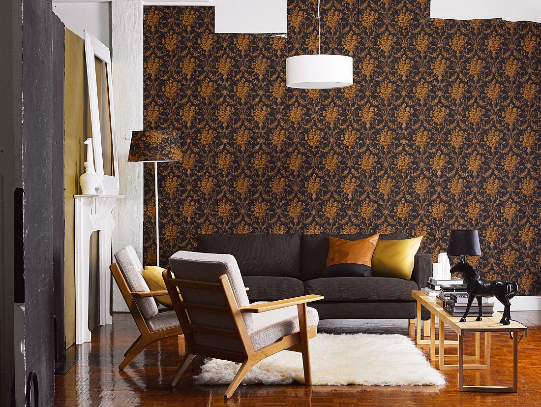 Wohnzimmer mit dunklem Sofa, Sesseln im Fiftiesstil und Flokati vor eleganter, dunkel gemusterter Tapete