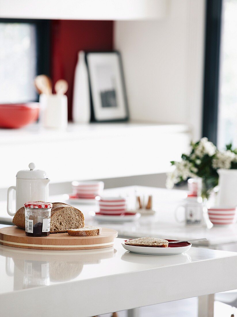 Frühstücksbrett mit Brot und Marmelade auf der spiegelnden Arbeitsfläche einer Küchentheke