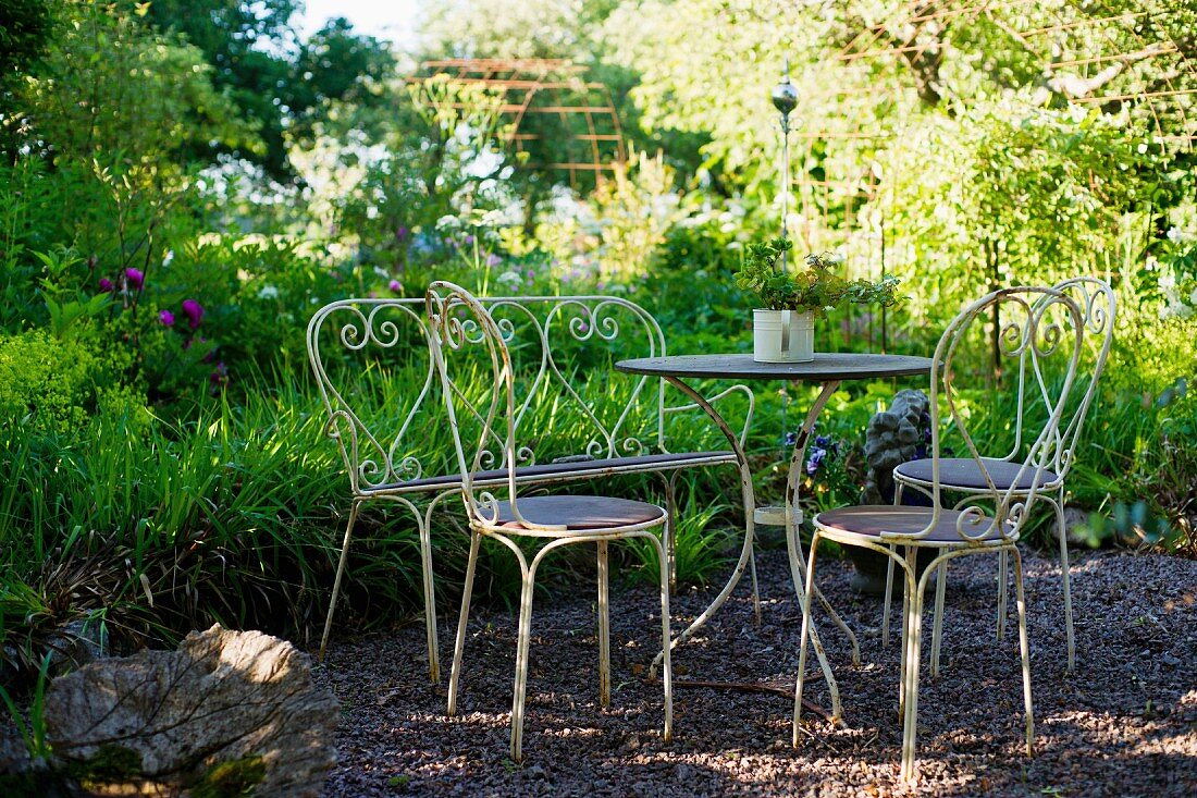 Idyllischer Vintage Sitzplatz auf Kiesfläche im Garten mit Bistromöbeln aus Metall