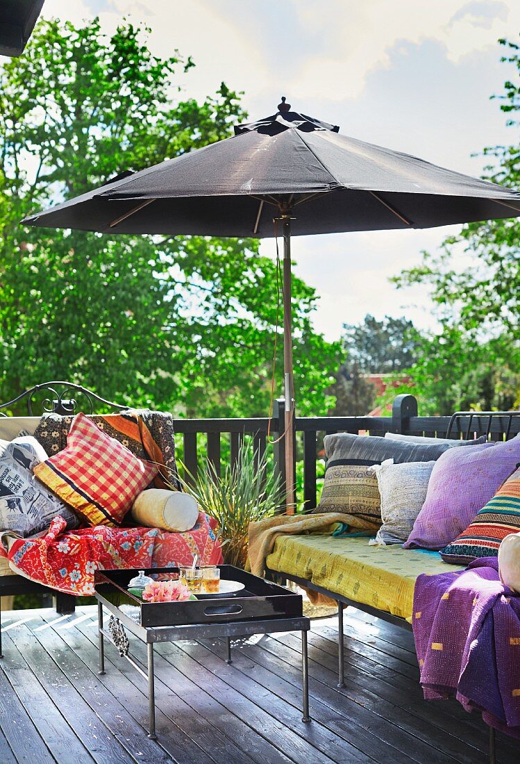 Sitzbänke mit Kissen und Sonnenschirm auf Terrasse in orientalischem Stil