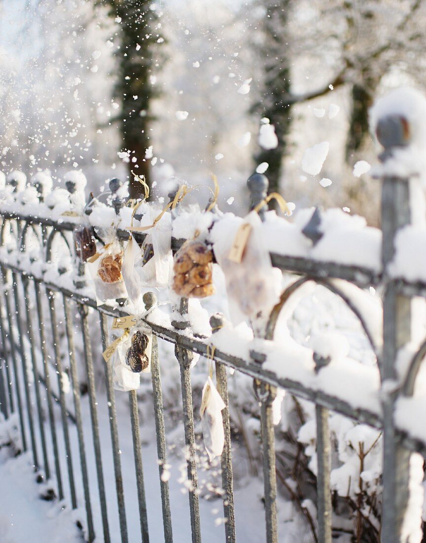 Small bags of biscuits hanging on snowy fence as Advent calendar