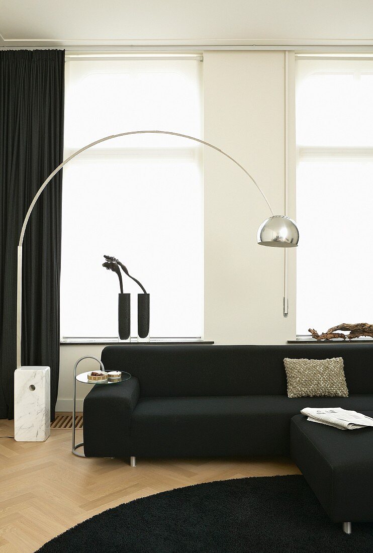Schwarz-weiss eingerichtetes Wohnzimmer mit Designer-Bogenlampe