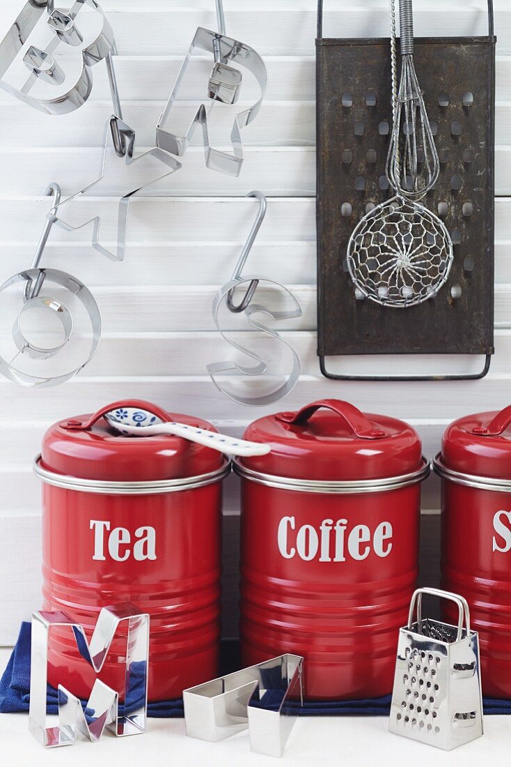 Küchendekoration mit roten Vorratsdosen für Tee und Kaffee, Buchstaben-Ausstecher und Küchenreibe