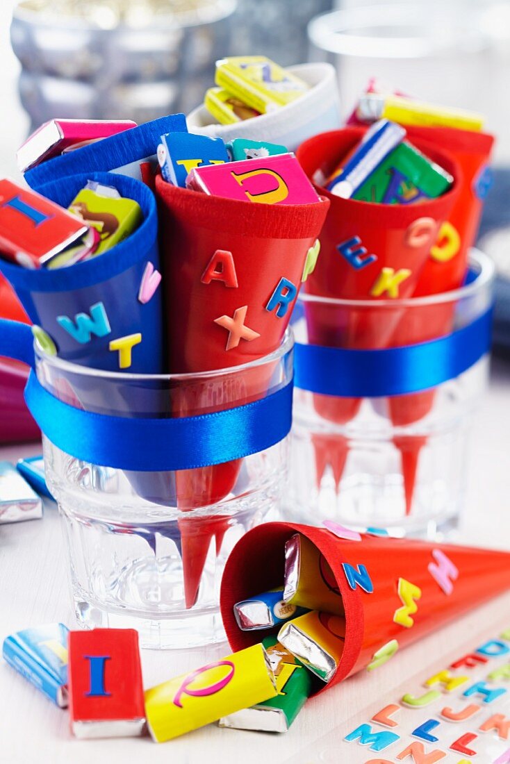 Small, colourful cones decorated with letters and holding bars of chocolate