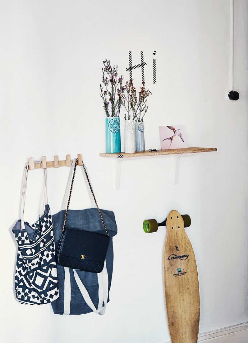 Garderoben Stillleben mit Keramikvasen auf Wandbord, Taschensammlung an Hakenleiste und Vintage Skateboard