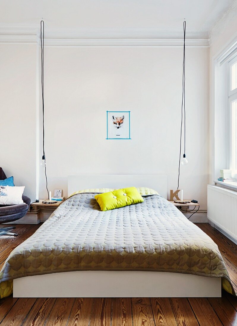 Bett mit Überwurf und Dekokissen im dänischen Design, flankiert von DIY Nachttischen und Glühbirnen an langen Kabelstricken