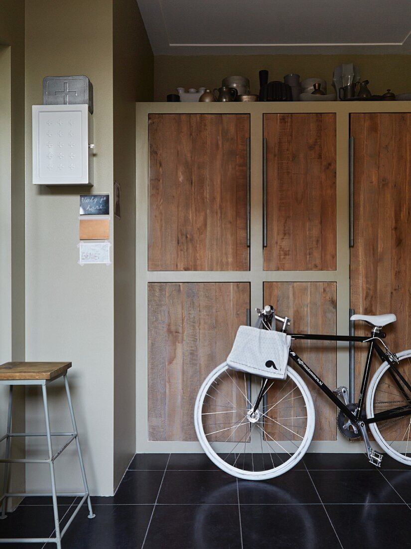 Bicycle in utility room in front of fitted cupboards with simple oak doors