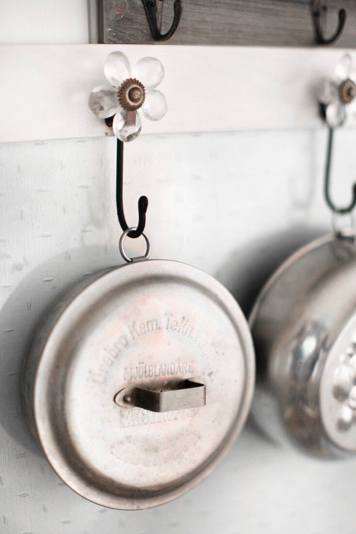 Metal pots and pans hanging from flower-shaped wall hooks