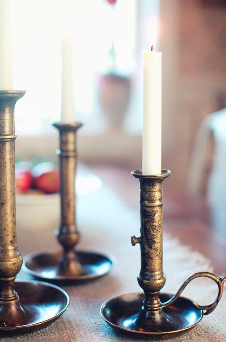 Lit candles in nostalgic, patinated brass candlesticks