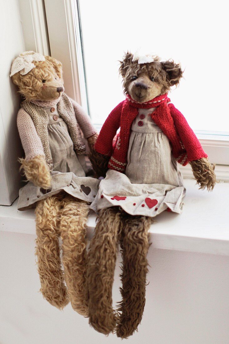 Teddy bears wearing winter clothing sitting on windowsill