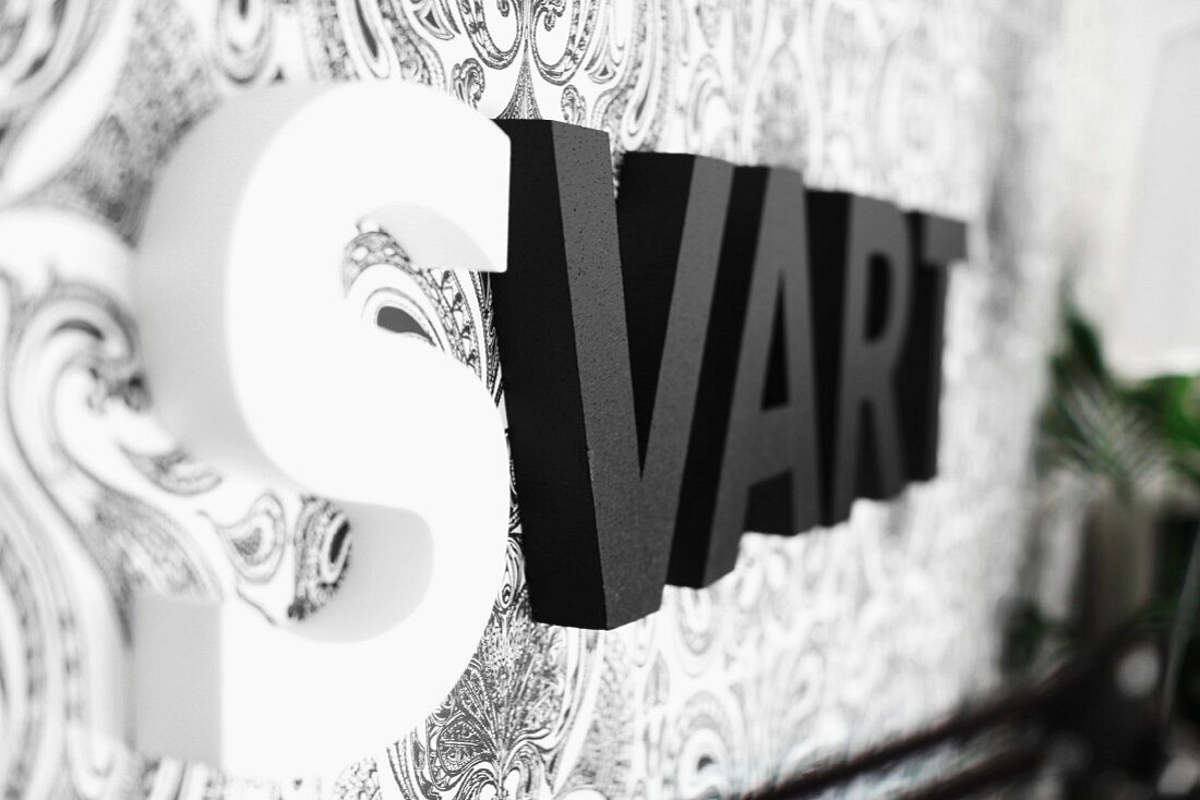 Black and white ornamental letters on wallpapered wall