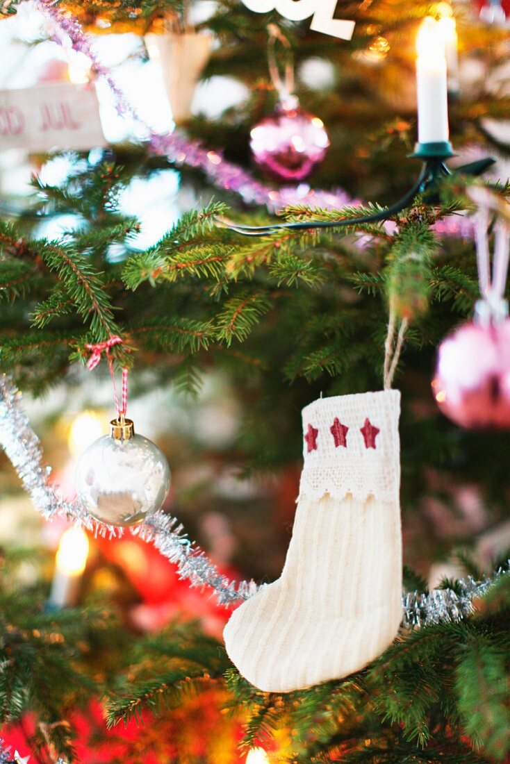 White baby's socks with stars hanging on decorated Christmas tree