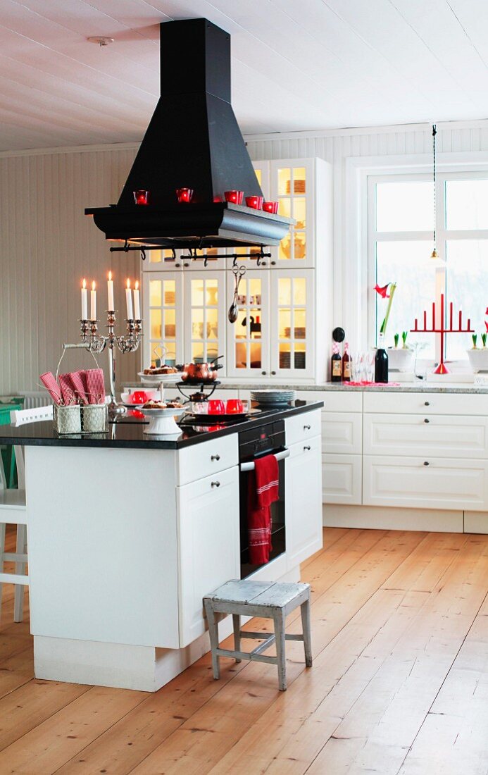 Black extractor hood above kitchen counter with white base unit on wooden floor in Scandinavian country-house kitchen