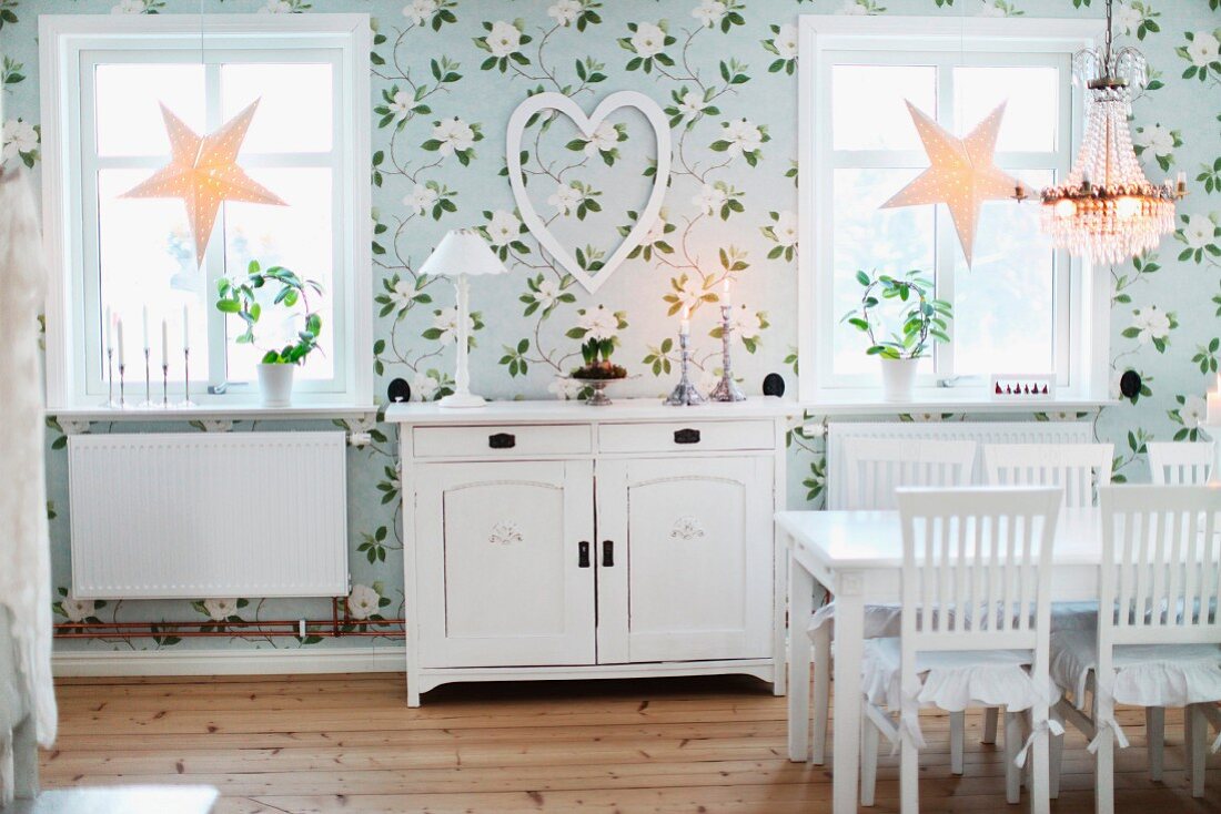 Esszimmer mit Blumentapete, weiss lackierte Möbel im Landhausstil, am Fenster weihnachtliche Sternen-Deko