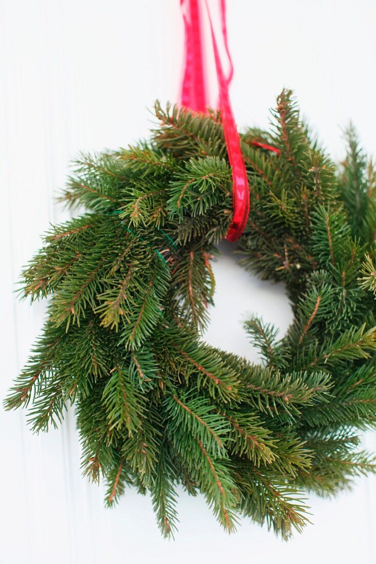 Wreath of fir branches hanging from red ribbon