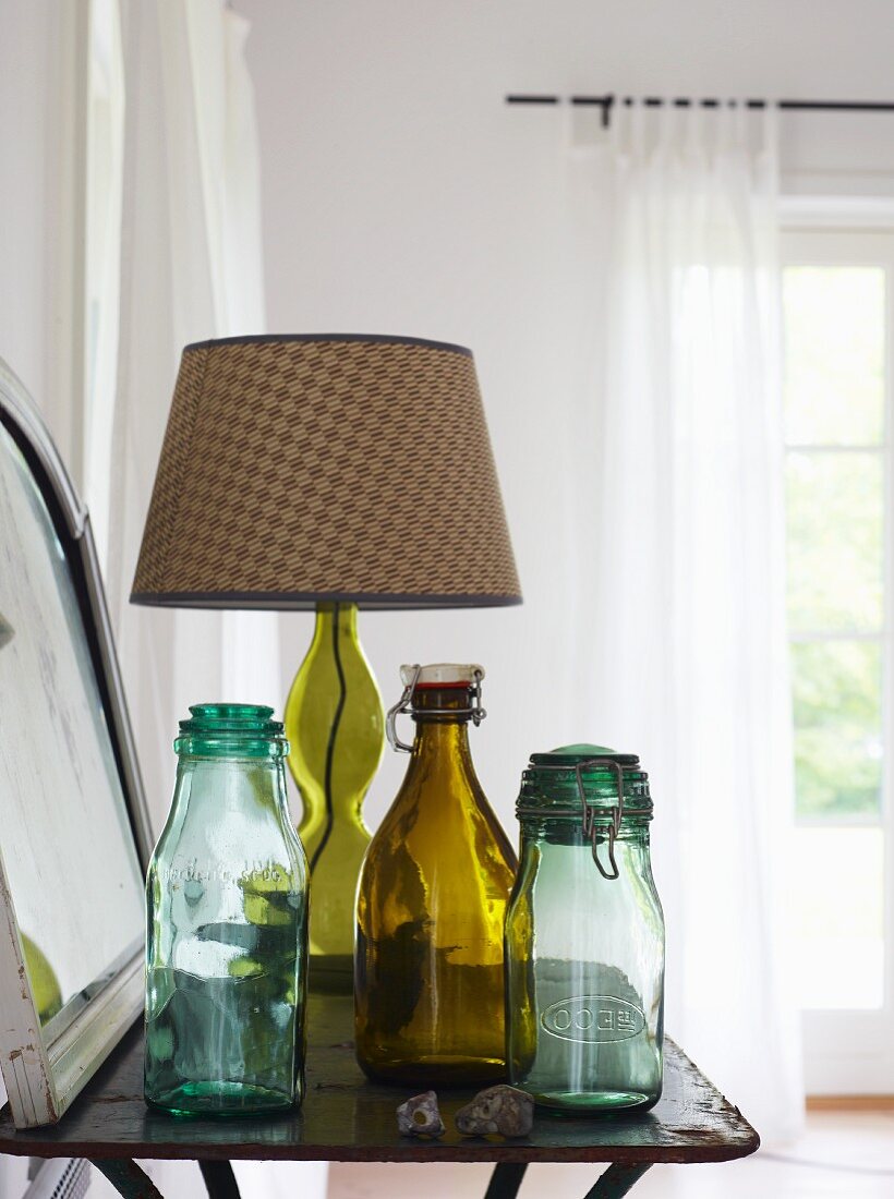 Vintage swing-top bottles and table lamp with checked lampshade on side table
