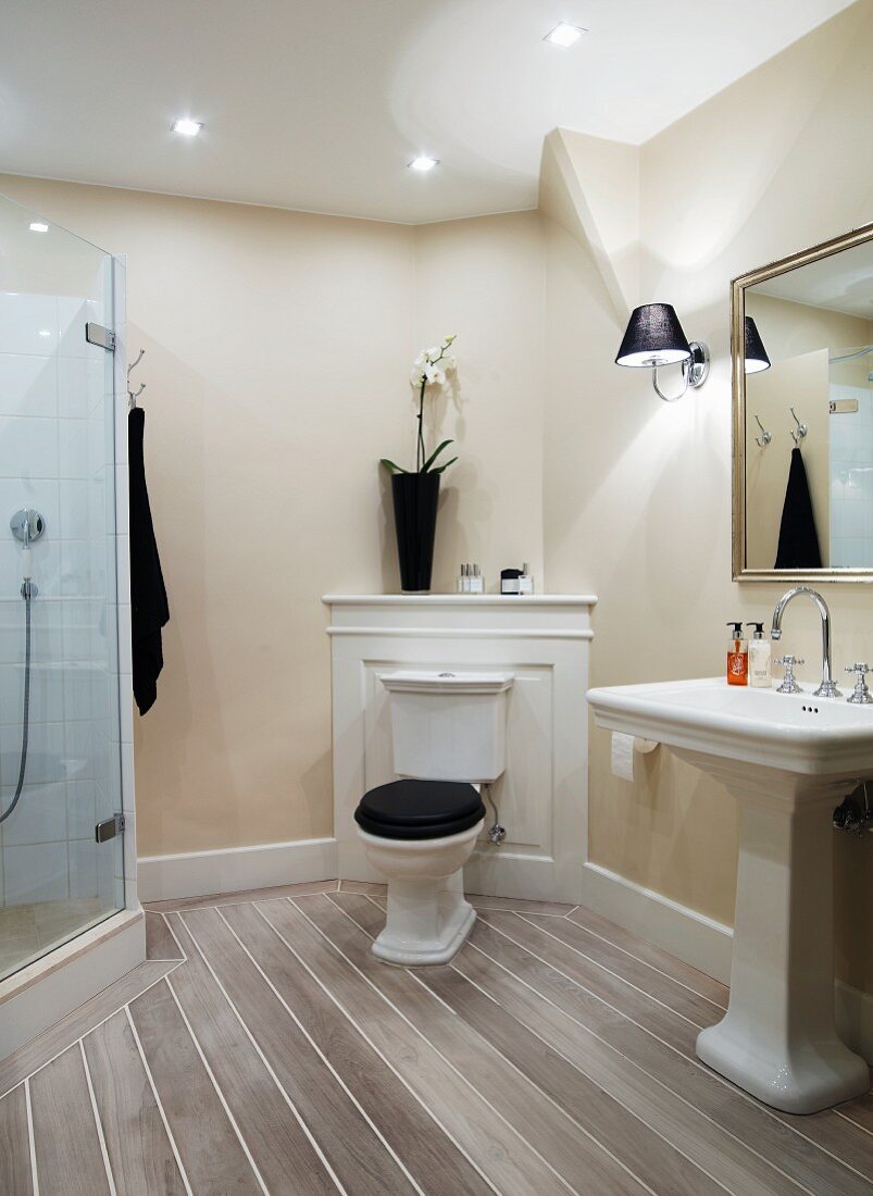 Traditionelles Bad, Stand-WC mit Spülkasten vor Holzpaneel in Zimmerecke, seitlich Standwaschbecken, gegenüber moderne Glas Duschkabine