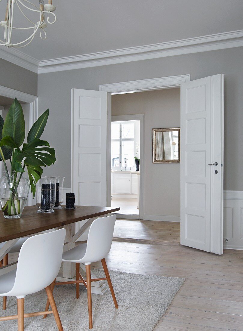 Essplatz mit Schalenstühlen im Klassiker Stil gegenüber offene Flügeltür mit Blick in Küche einer Altbauwohnung
