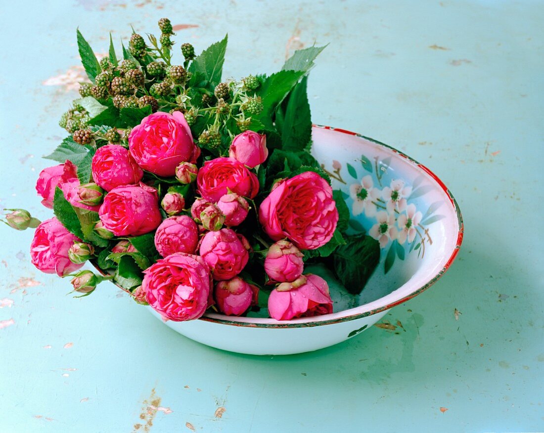 Rosenblüten und Brombeerzweige in einer Schale