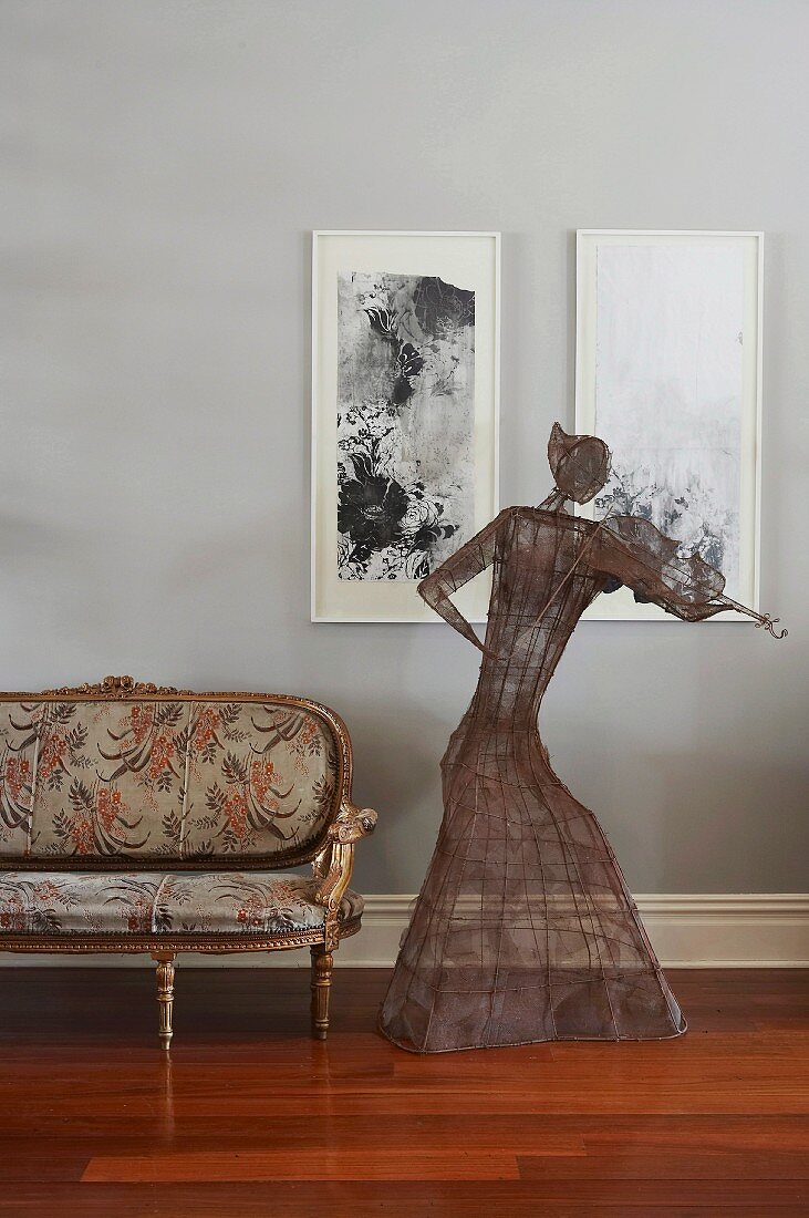 Wore sculpture of woman playing violin in front of modern paintings on wall and next to Rococo couch