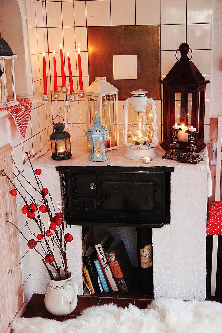 Eingemauerter Kaminofen mit Vintage Laternen und Kerzenständer mit roten Kerzen