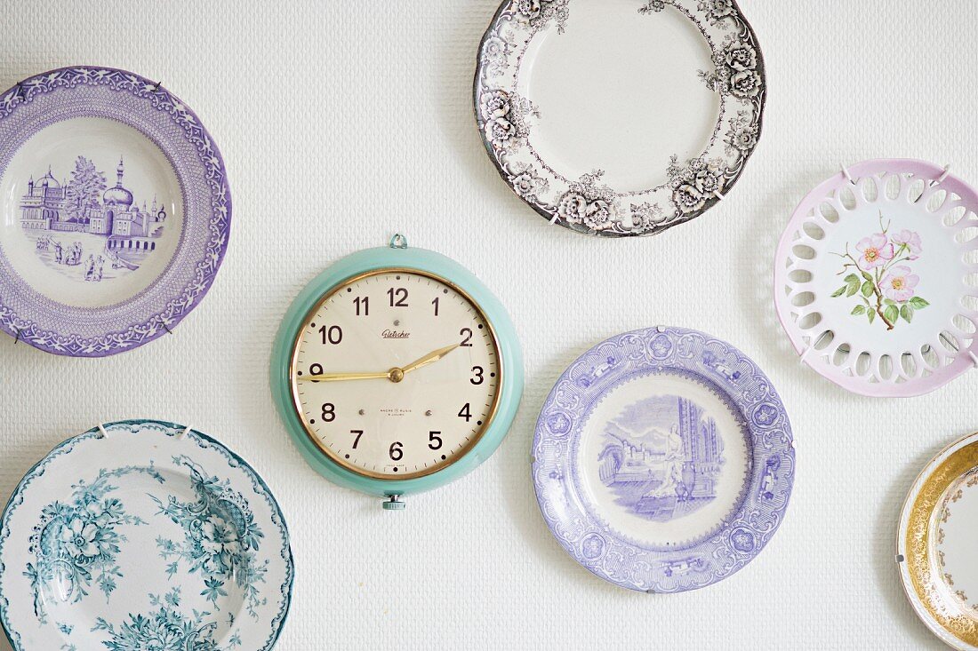 Collection of plates with rustic motifs and retro clock on wall