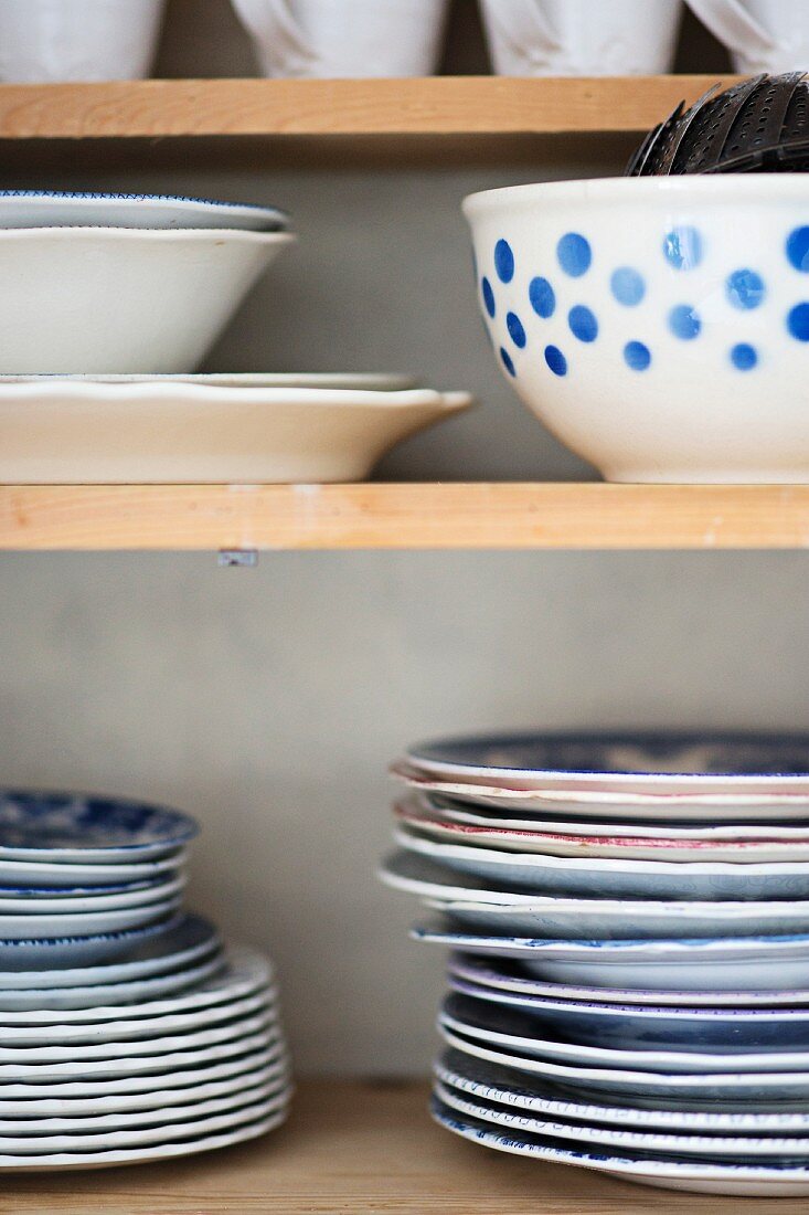 Stacked plates and bowls on wooden shelves