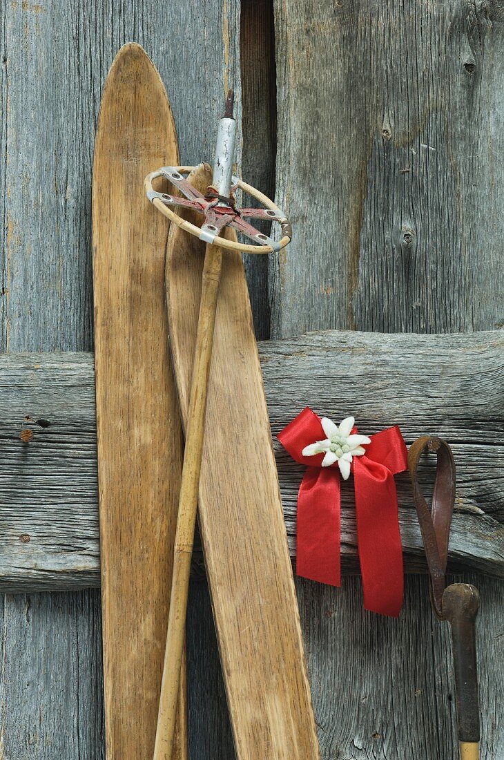Antique skis and ski poles leaning on wall next to Christmas decoration