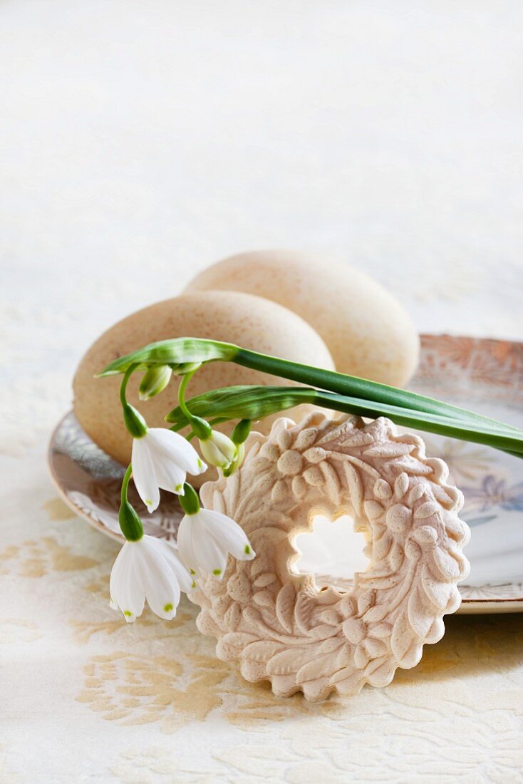 Two blown turkey's eggs on vintage plate with moulded aniseed biscuit and spring snowflake flowers