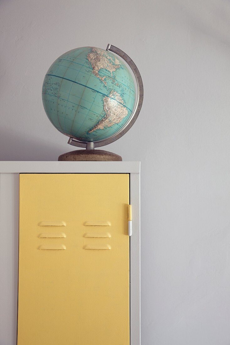 Old globe on white vintage locker with door painted pastel yellow
