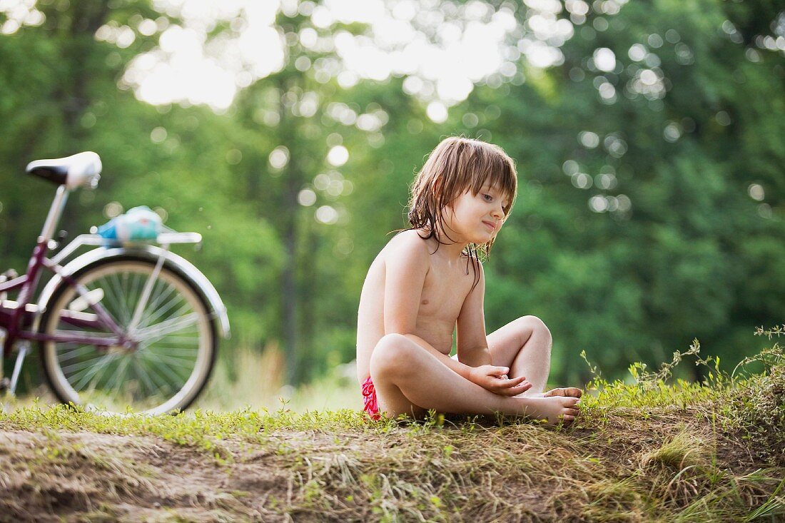 A young girl resting on the floor next to a bicycle